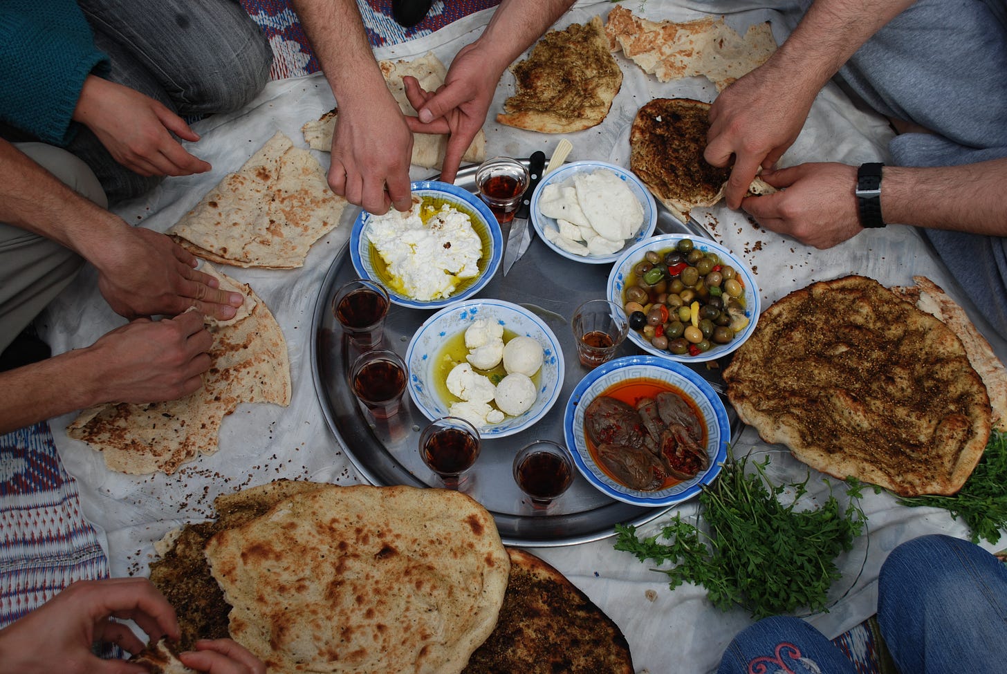 People sharing lunch, flat bread, goats cheese, olives and parsely