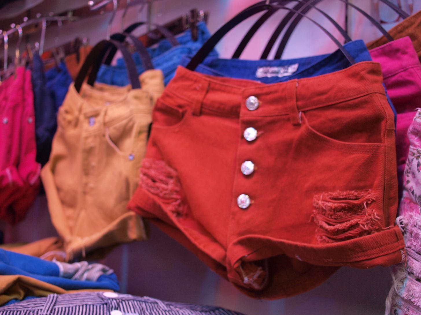 Photo of cheap, colourful cotton shorts hanging up in a shop.