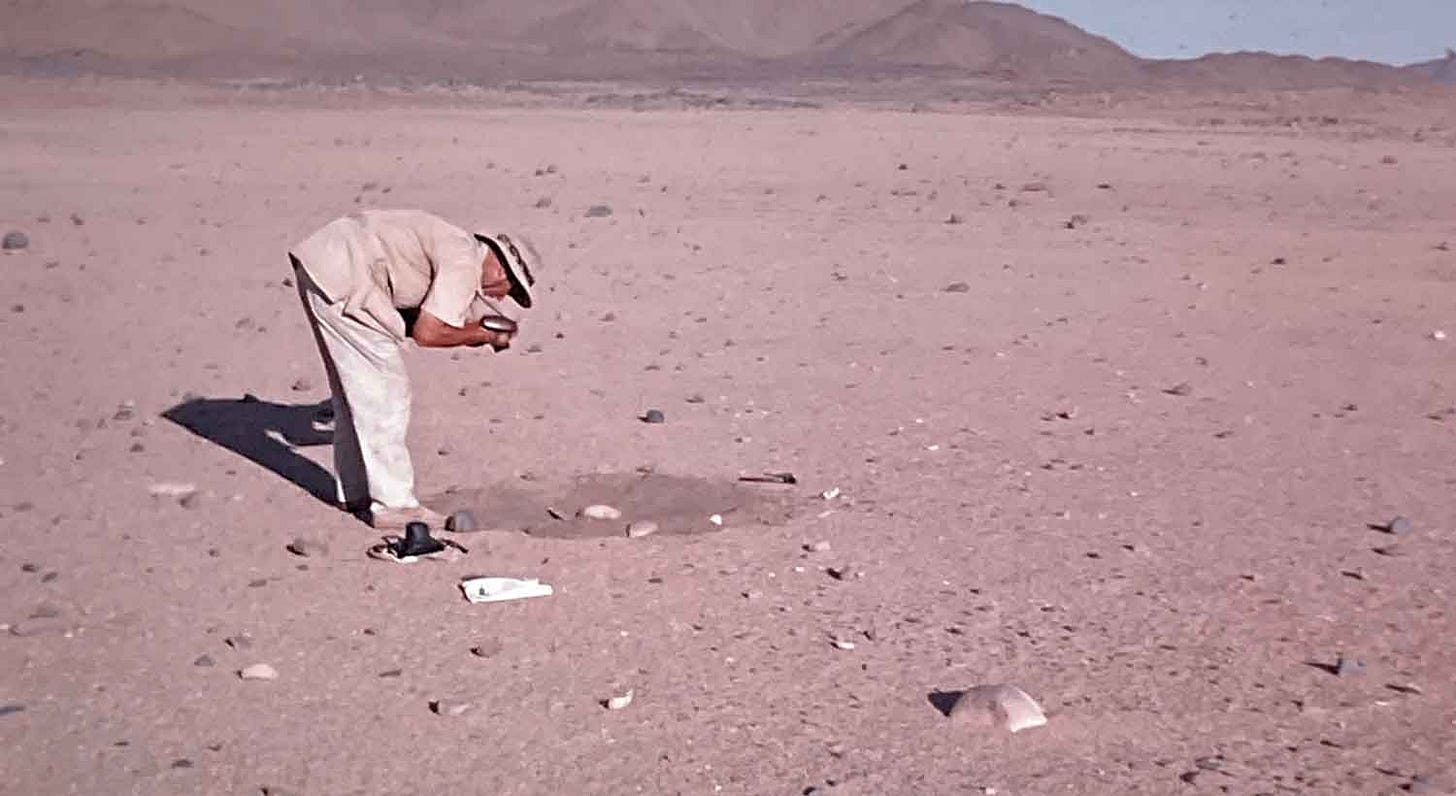 J. Desmond Clark photographing artifacts on a desert landscape