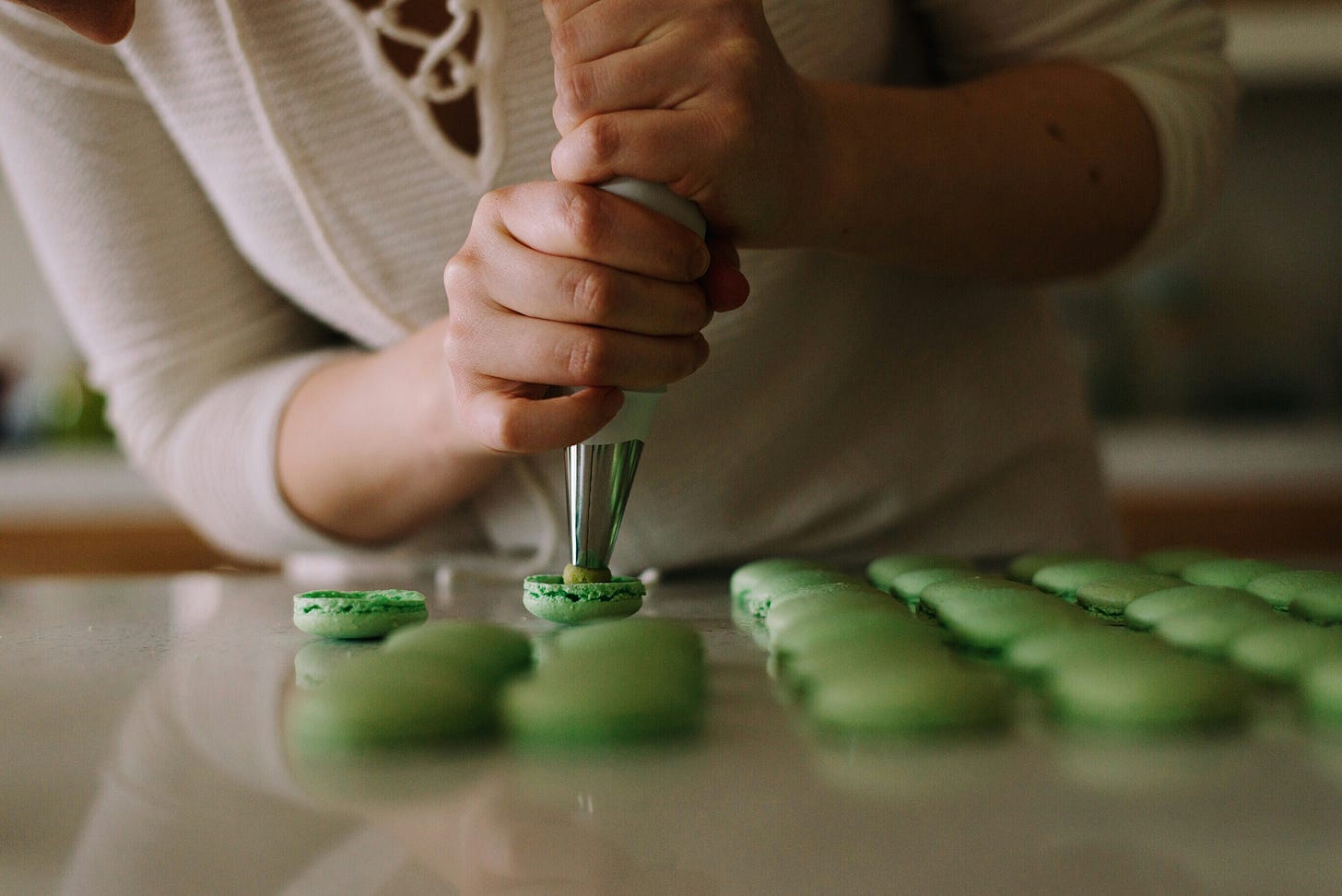 A woman pipes icing on to macarons