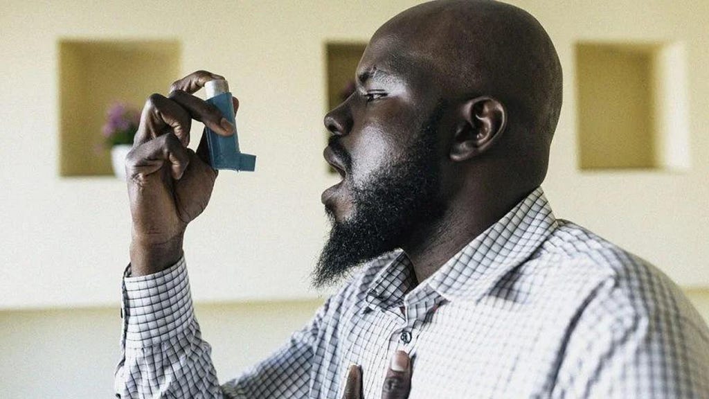 A black man using an asthma inhaler