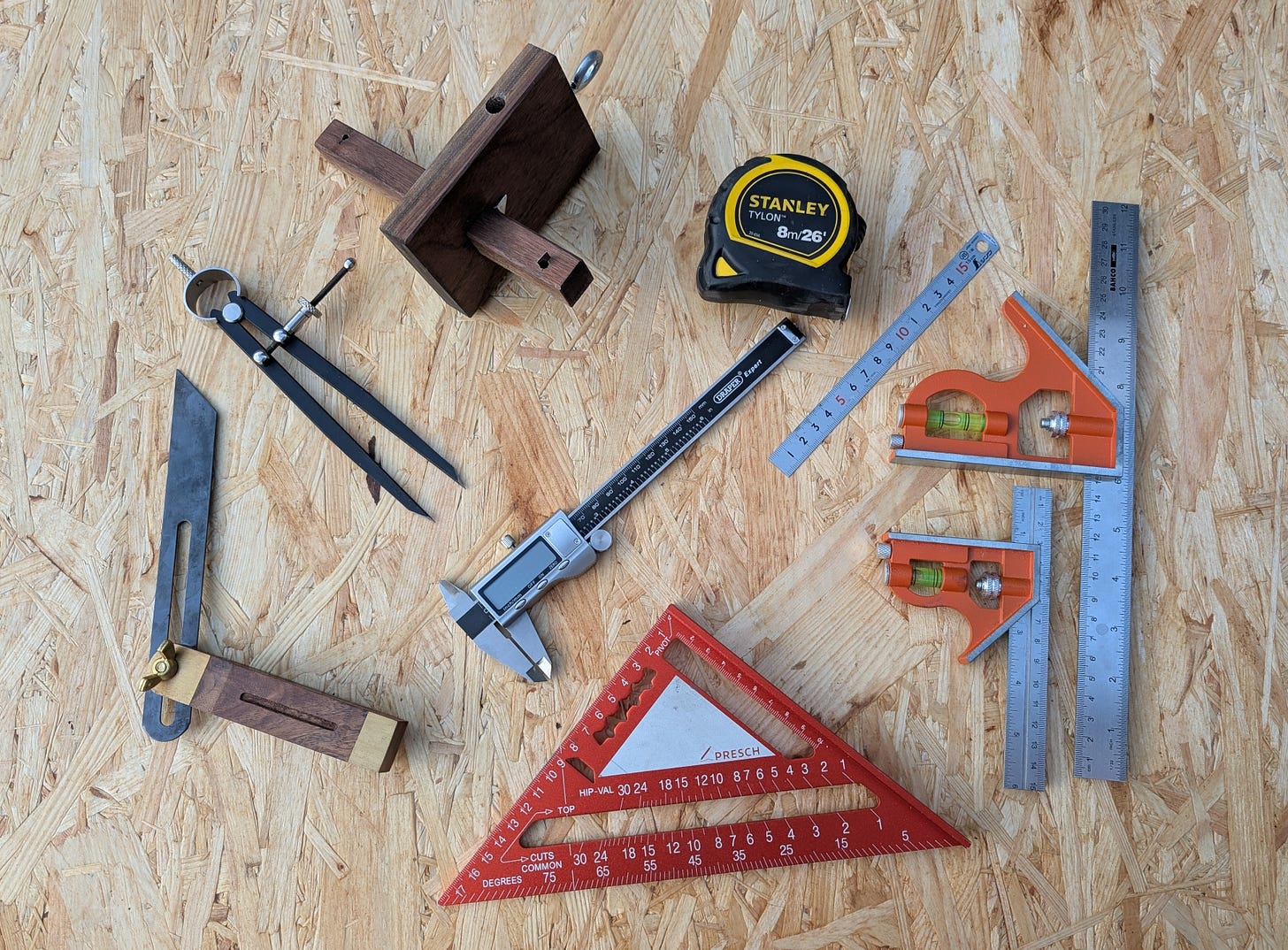 Combination square, steel rule, marking gauge, and tape measure, essential for accurate woodworking.