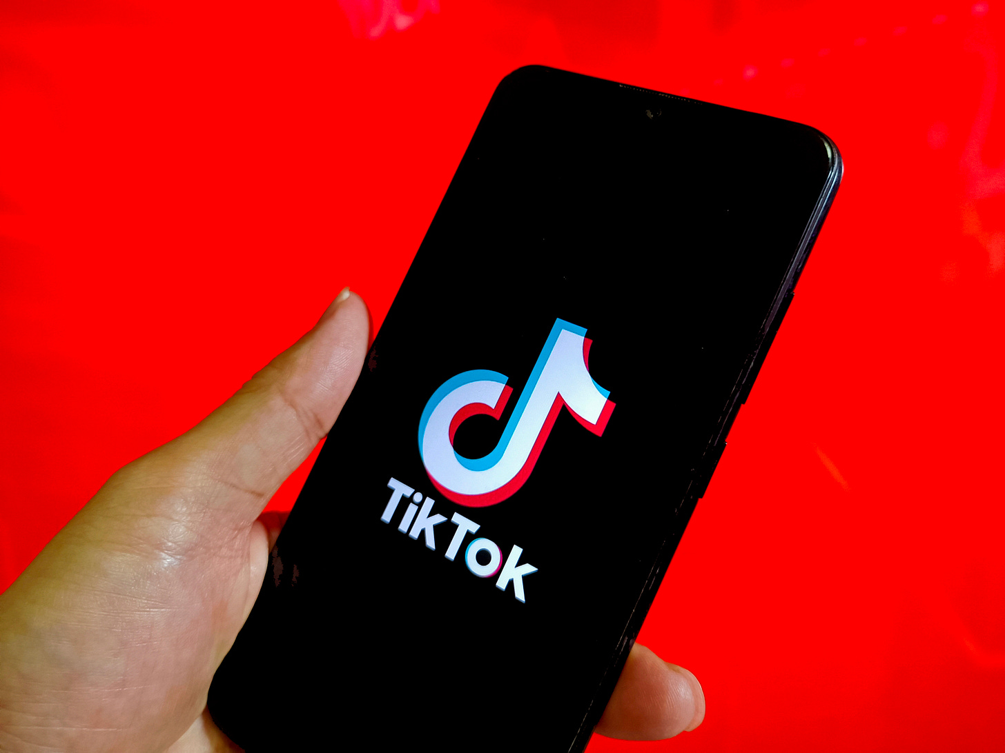 The TikTok splash screen on a smartphone against a red background (CFOTO / Future Publishing via Getty Images)