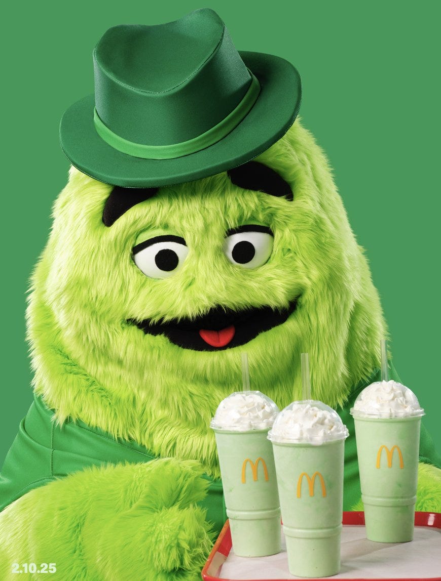 A green grimace in a hat serving up shamrock shakes