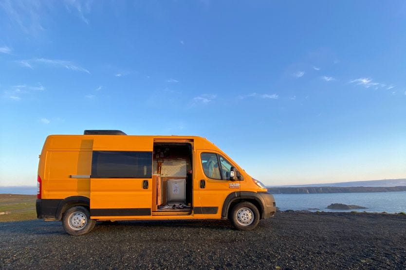 Hermes, the yellow converted camper van, sits on an ocean cliff in the morning light in Bonavista Newfoundland