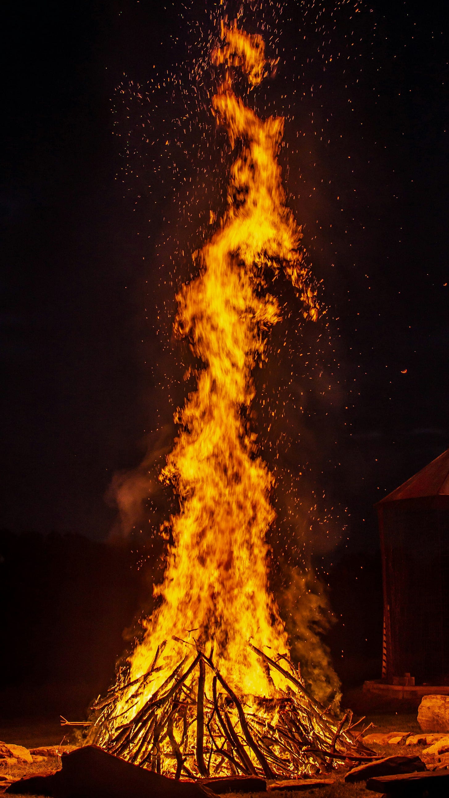 Tall orange bonfire against black sky