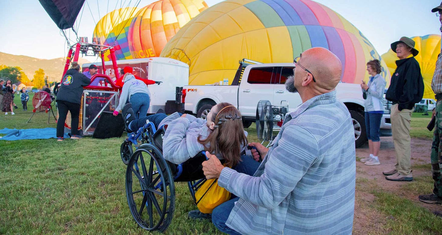 Wheelchair user looks up to see hot air balloon filled with air.