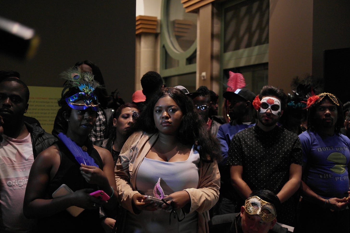 A photograph of ballroom participants attending a ball. Pictured participants appear to be Black and some are wearing masquerade style masks.