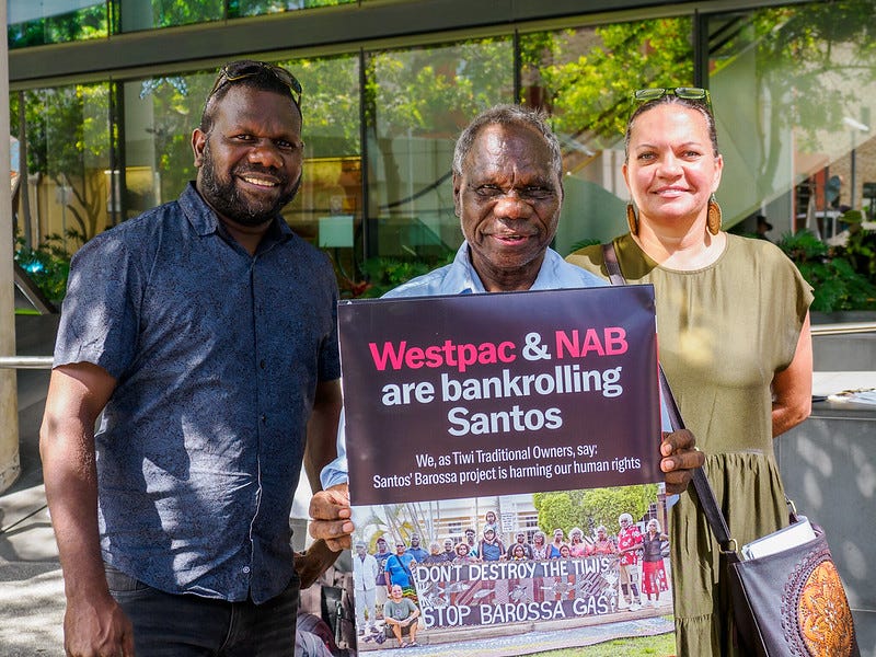 Photo of three Tiwi Islanders with a placard outside Westpac AGM, Brisbane Convention Centre