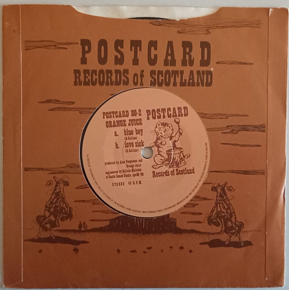 A vinyl single with Blue Boy on the A side and Love Sick on the B side. It's in a brown "Postcard Records of Scotland" sleeve.