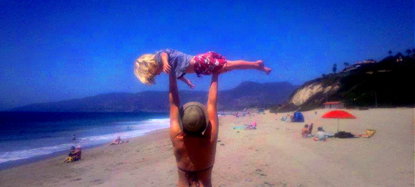 the author as a young mother, holding her son up in the air while he planks