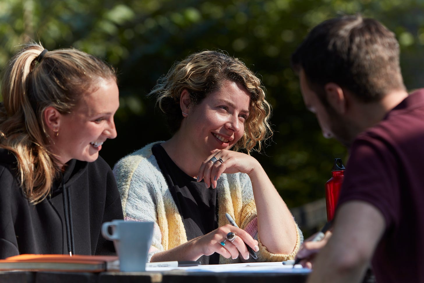 Dr Alexa Haynes, middle, listening intently during a design research session, sitting outside, in the warm summer sun. Remember that? When it was warm?