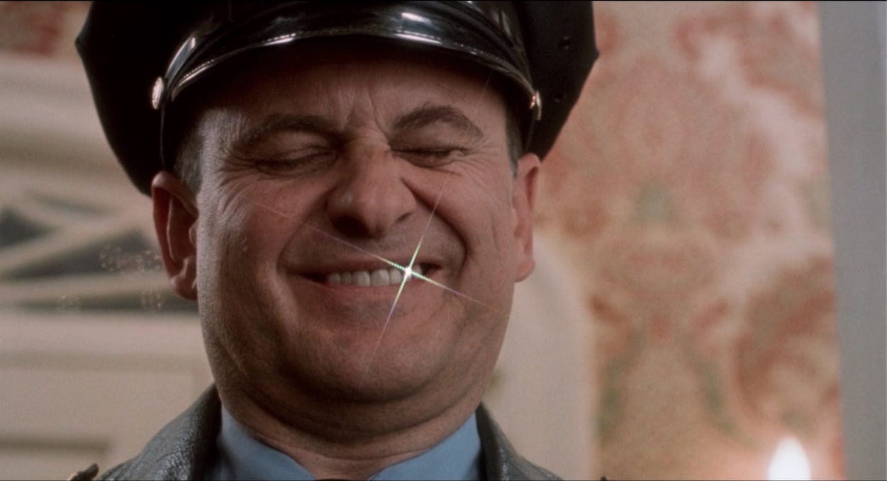 Harry in Home Alone (as played by Joe Pesci), dressed as a cop, his gold tooth shining