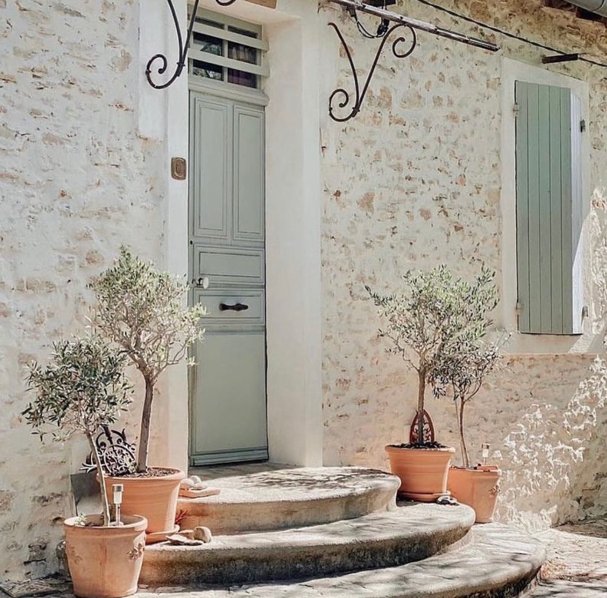 Mediterranean entrance with sage green front door and stoned wall 