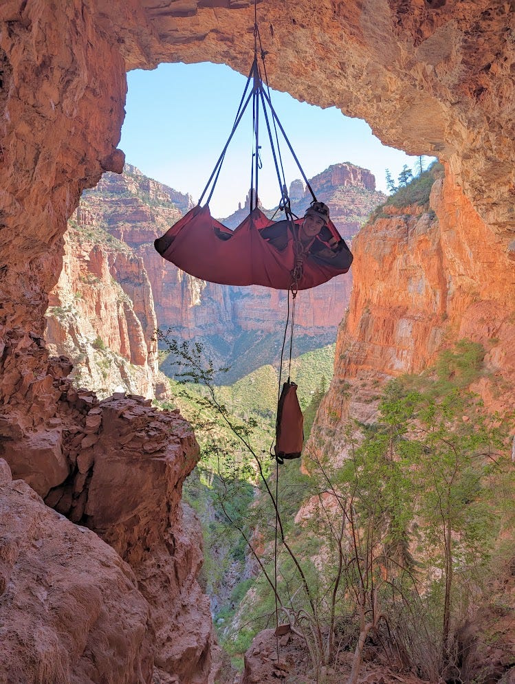 Sam in a portaledge-hammock hanging from a rope in the large entrance to Silent River Cave