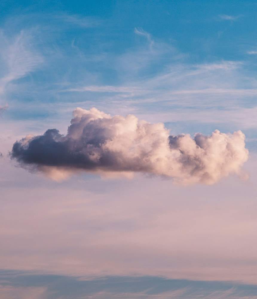 Photo of a large cloud hanging in a mostly clear blue sky.