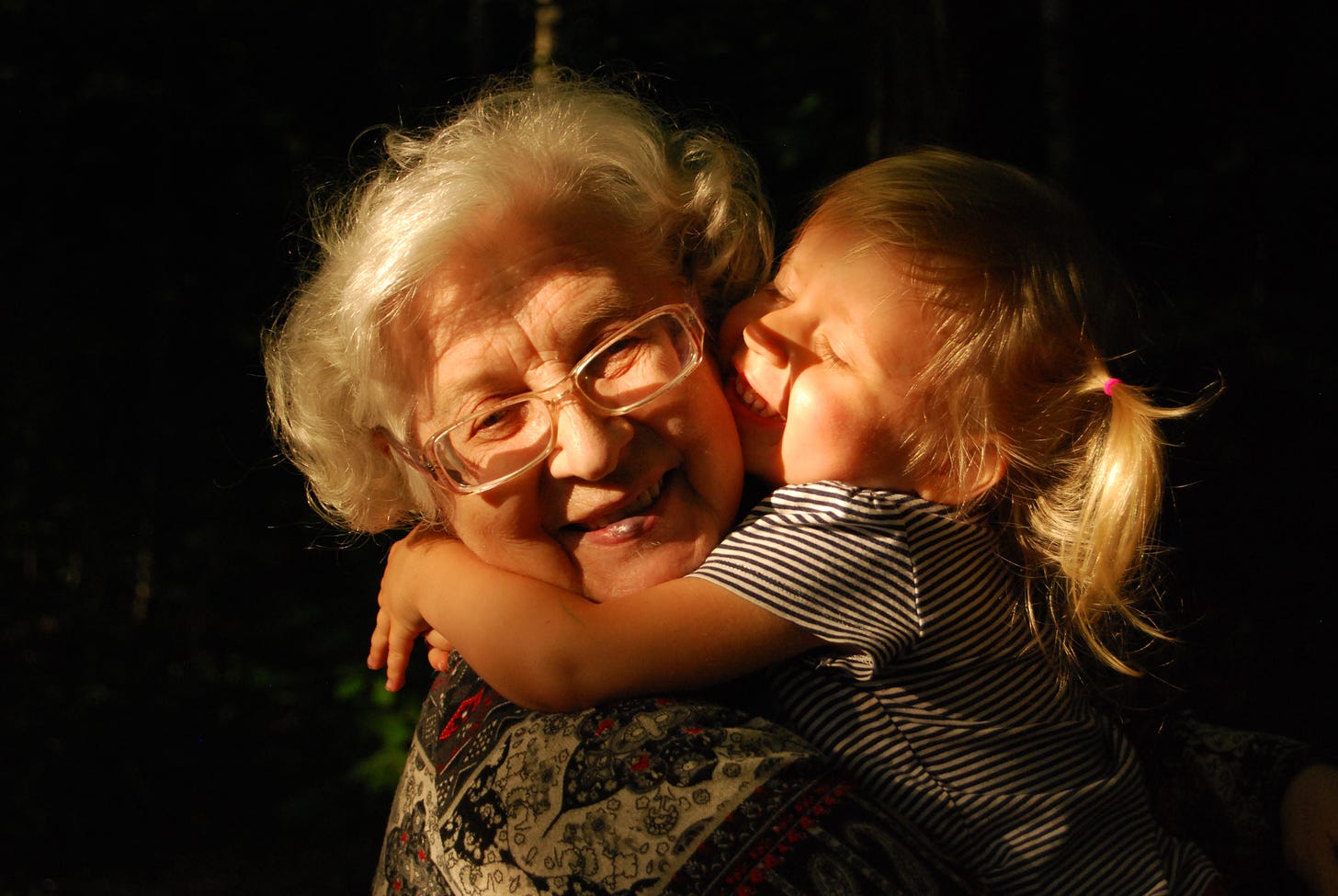 Small child embracing an older woman with gray hair.