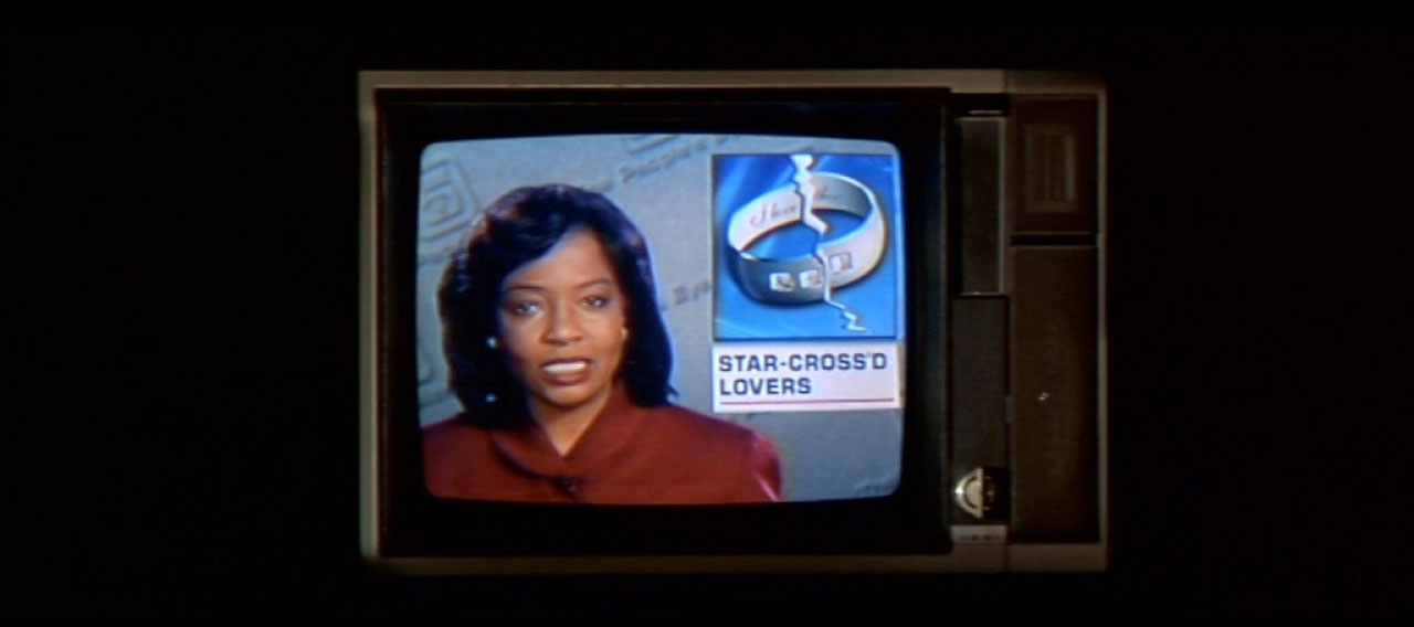 Still from Baz Luhrmann's 1996 Romeo + Juliet. A newsreader is reading the prologue from the play