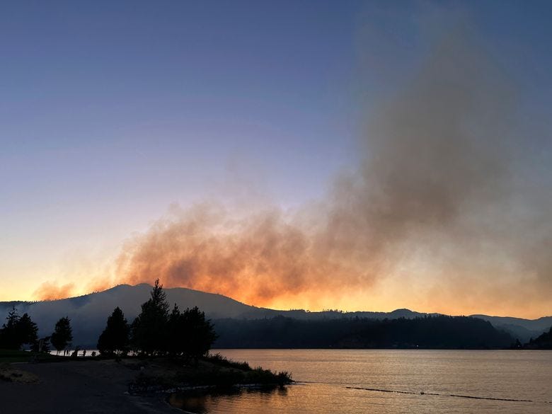 Smoke from a wildfire in the Columbia River Gorge in Washington state rises in the background in this view, Hood River, Ore., Sunday, July 2. Authorities have more than doubled the number of people battling the wildfire that has burned some homes and forced the evacuation of hundreds of others in southwestern Washington near the Columbia River Gorge.