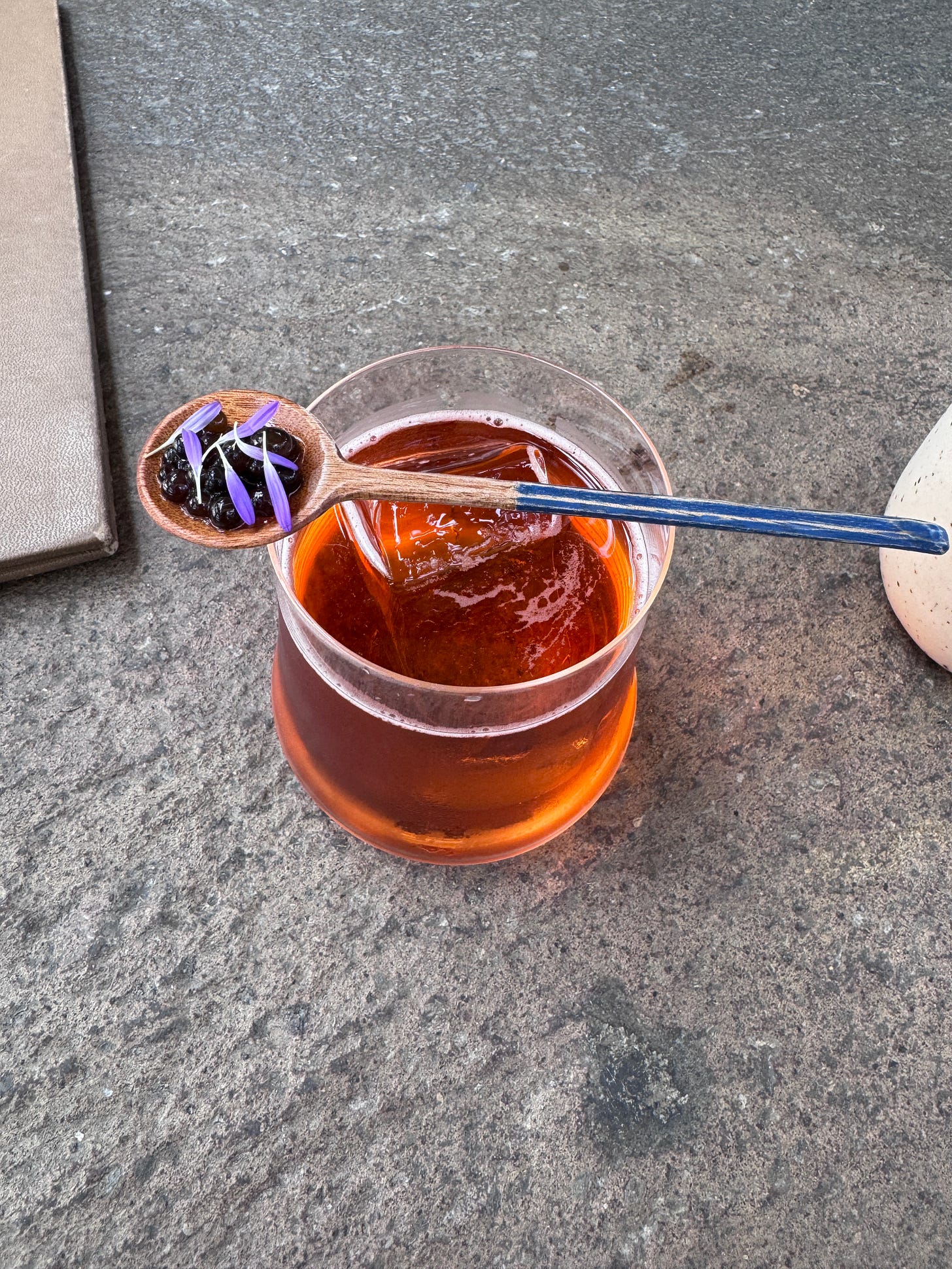 Overhead view of a cocktail with a spoonful of cushuro over the glass