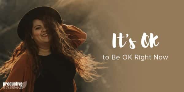 A woman smiling with long brown hair turns toward the camera wearing a hat, her hand holding it in place. Text Overlay: It's OK not to be OK right now.