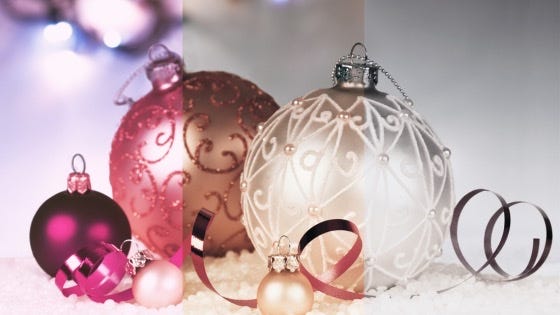 A collection of glittery, pink and champagne Christmas balls and ribbons gradually fades to black and white across the page.