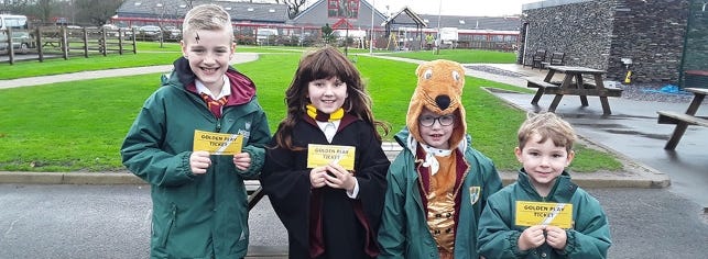 schoolchildren in character costume proudly displaying their school's gold ticket incentives for reading