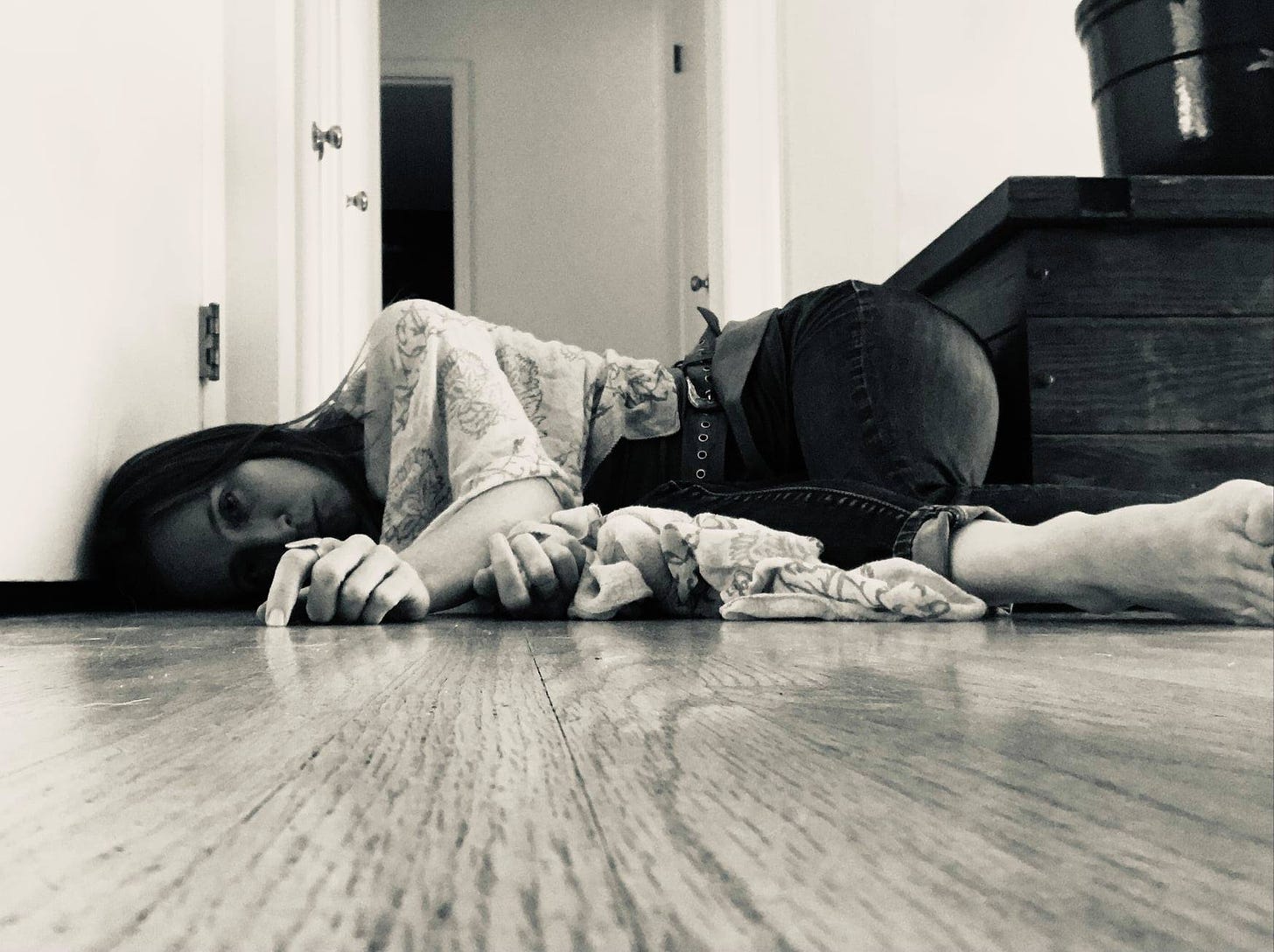 black and white photo of the author lying on the floor in a doorway, on her side facing the camera