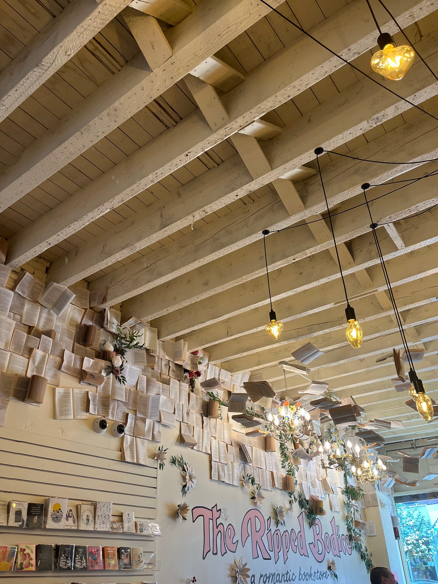 a photo of the interior of a bookstore, the ripped bodice. there are books and pages hanging all over the store and papered on the walls.