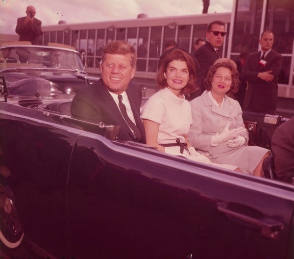 President and Mrs. Kennedy and Nellie Connally are seated in the Presidential Lincoln limousine shortly before departing from the airport.  Governor Connally’s shoulder is visible on far right.  (MS 360:  E-0009-140-B-16)