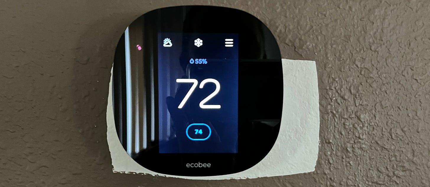 Photo of Ecobee thermostat mounted to brown-painted wall with a patch of white paint extending beyond the Ecobee device