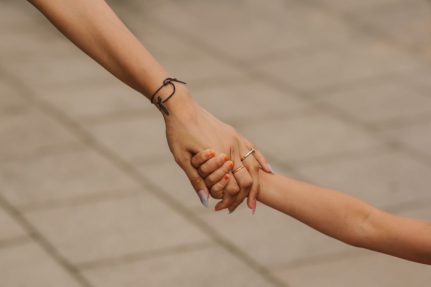 unrecognizable mother holding hands with daughter