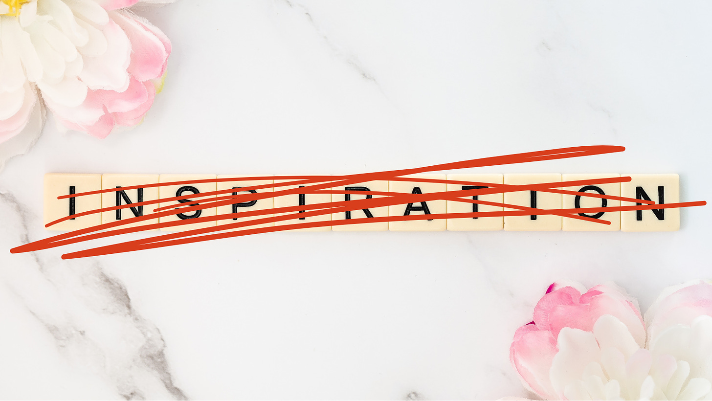 white background with pink and flowers. Scrabble tiles spell out the word 'inspiration,' but it's crossed out in red marker.