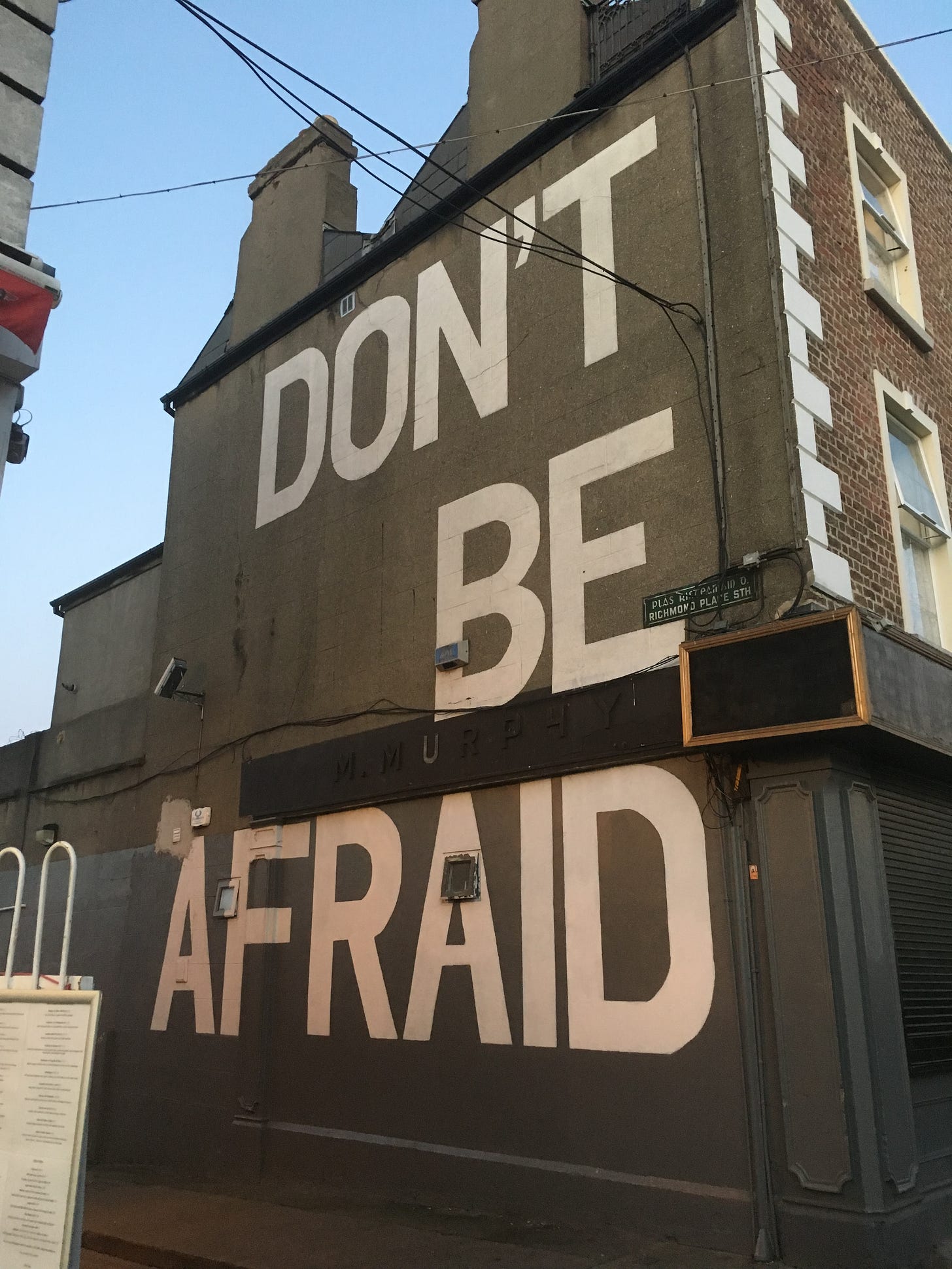 The words "DON'T BE AFRAID" in white paint on a brown building 