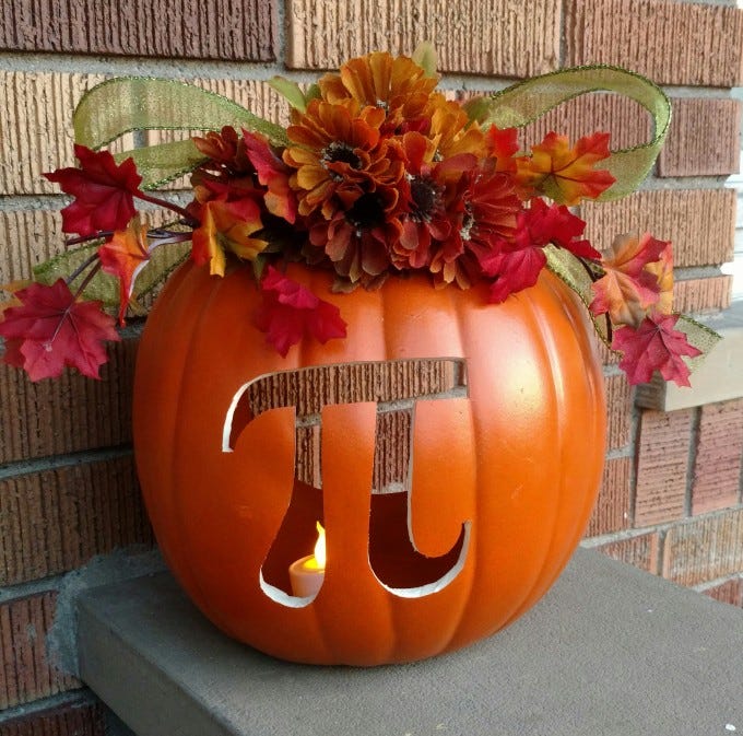 A craft pumpkin has fall silk flowers on top and the pi symbol carved into the front.