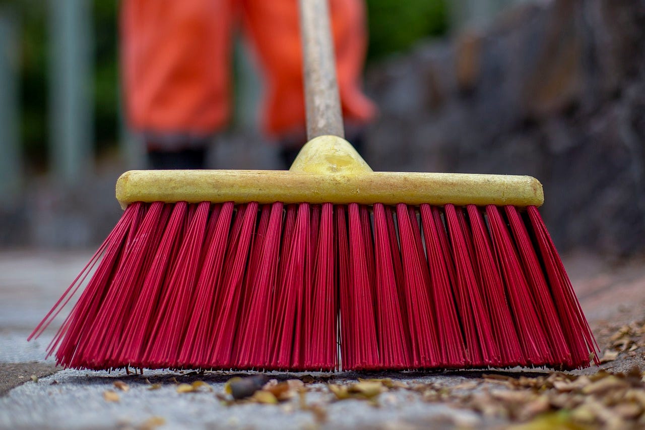A man cleaning up with a broom