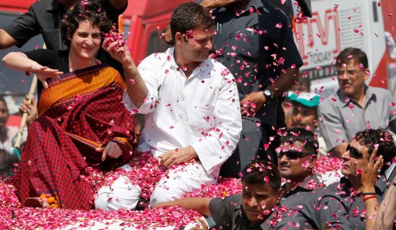 Vice President of Indias ruling Congress party Rahul Gandhi, second right, holds a handful of flower petals to throw back at supporters, with his sister Priyanka Vadra seated by his side as he arrives to file his nomination for the ongoing general elections in Amethi, in the northern Indian state of Uttar Pradesh, Saturday, April 12, 2014. Gandhi, heir to the country's Nehru-Gandhi political dynasty, is leading the struggling party's campaign in the general election. The multiphase voting across the country runs until May 12, with results for the 543-seat lower house of parliament announced May 16. (AP Photo/ Rajesh Kumar Singh)