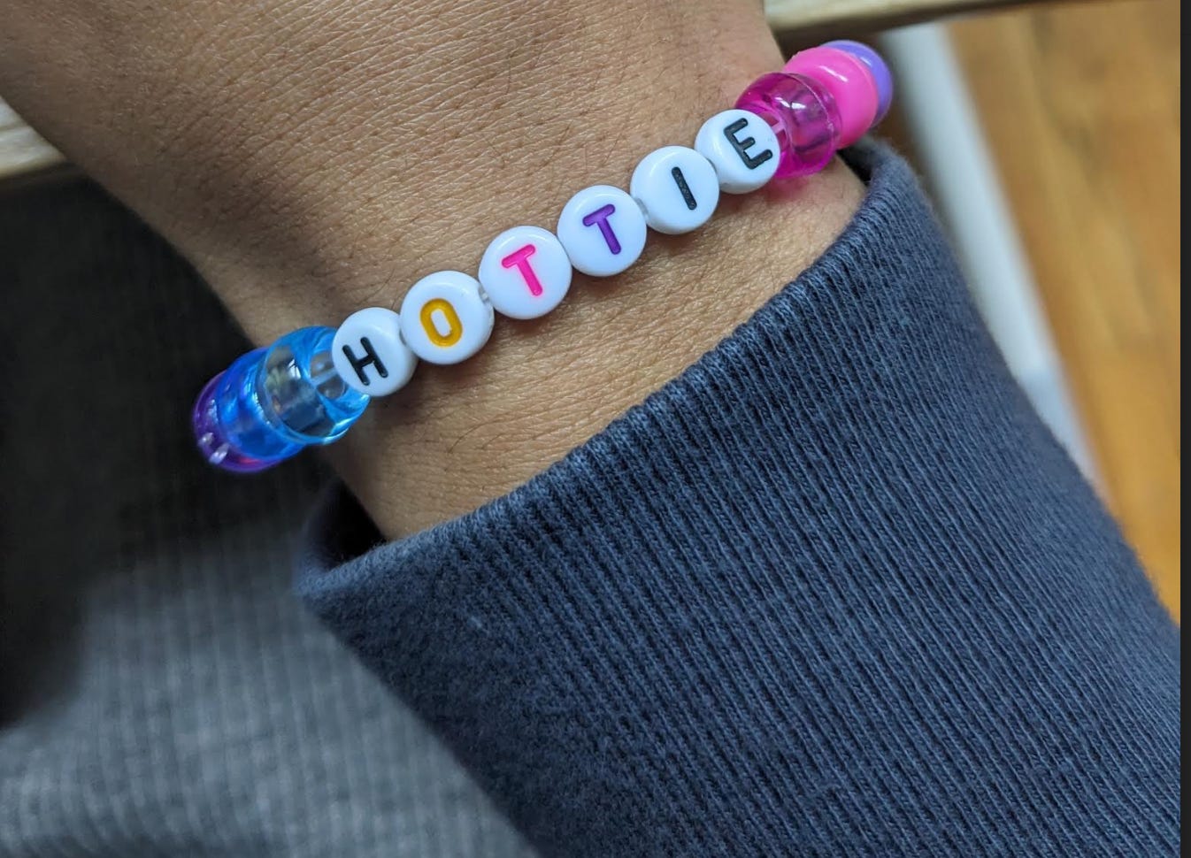 A handmade beaded bracelet is on Nathhalie's wrist. The beads are a mix of blues, pinks, and purples and the letters of the center beads read out, HOTTIE