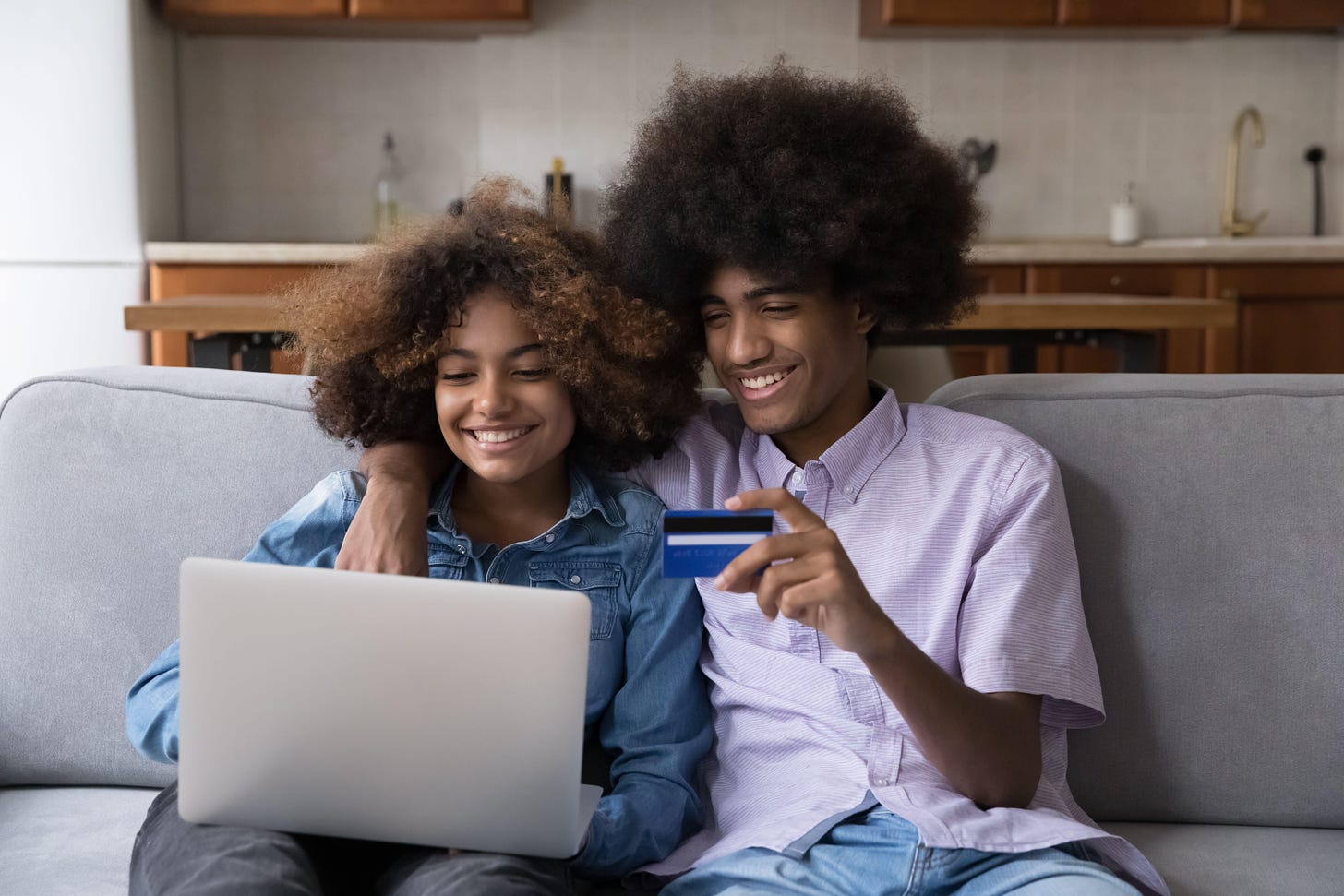 2HKY7CT Happy African gen Z teen student couple hugging on couch