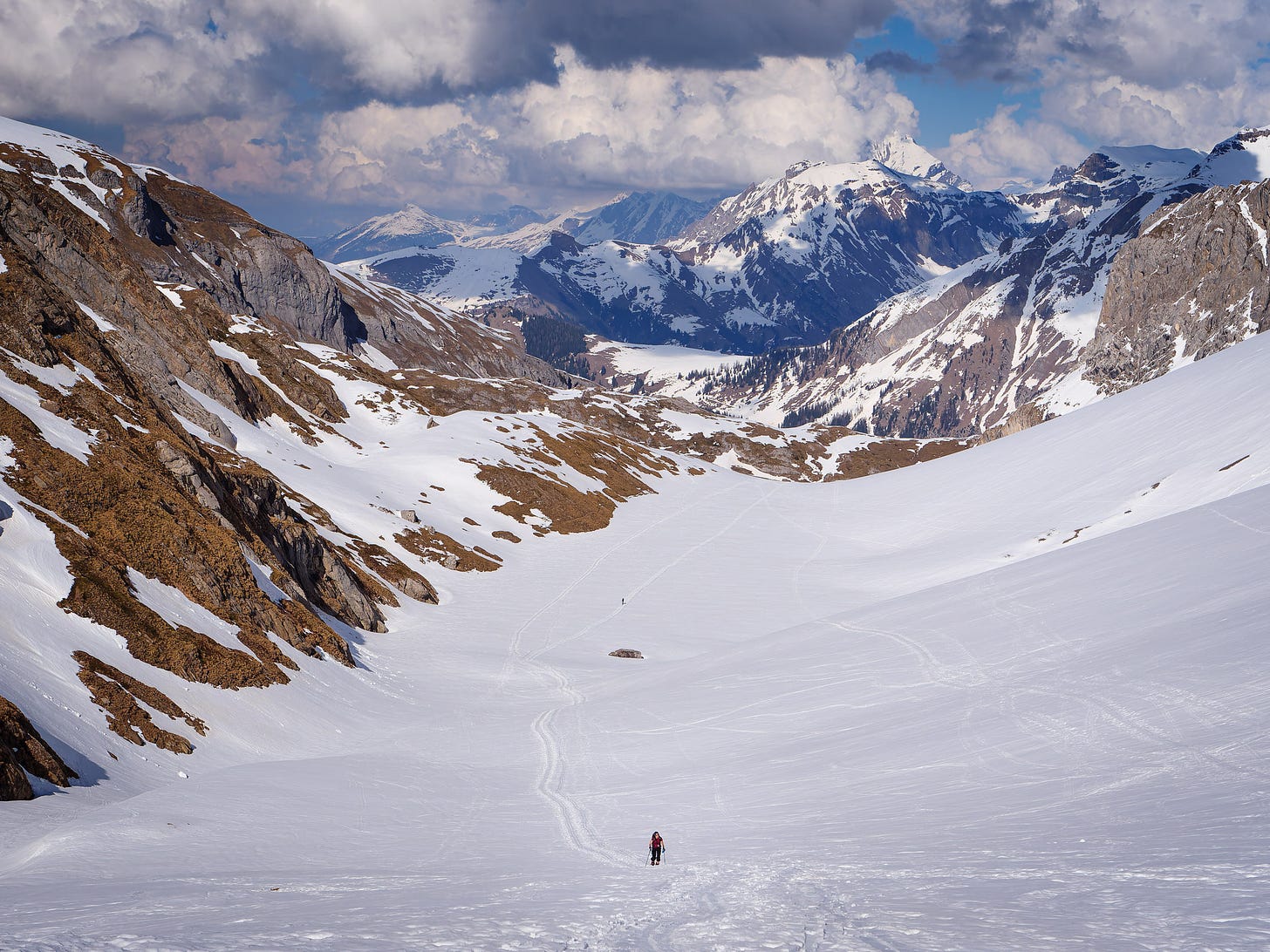 A lone ski tourer heading upwards in the snow covered mountains.