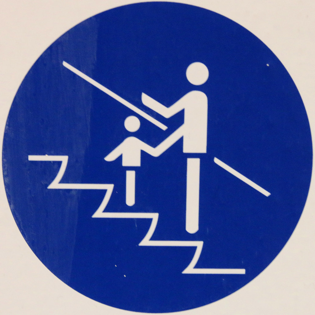 escalator warning sign showing the proper way to ride with a child