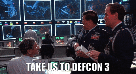 Animated GIF of WarGames. The General commands "Take us to DEFCON 3" inside the nerve center of the military facility. The sign is then shown to flip from green 4 to yellow 3.