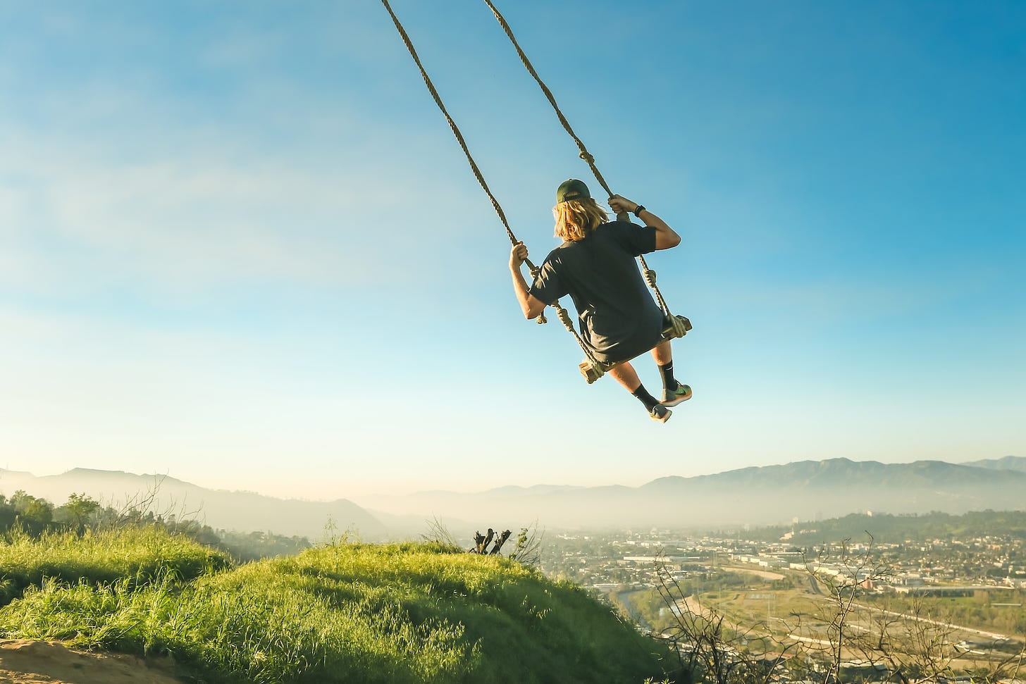 A person in a swing high above the landscape.