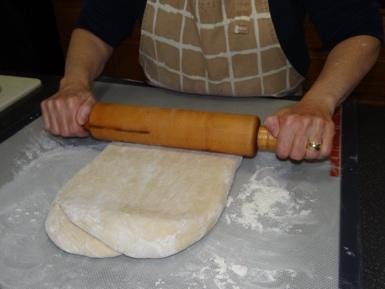 A person rolling dough with a rolling pin

Description automatically generated