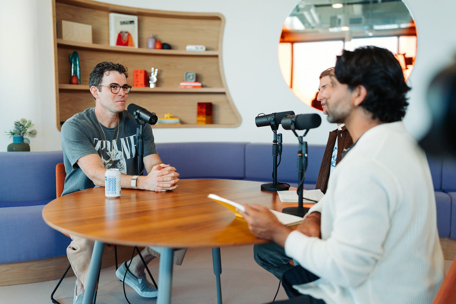 Instagram head Adam Mosseri sitting at a table with YouTubers Colin and Samir, there is a mic on the table in front of him