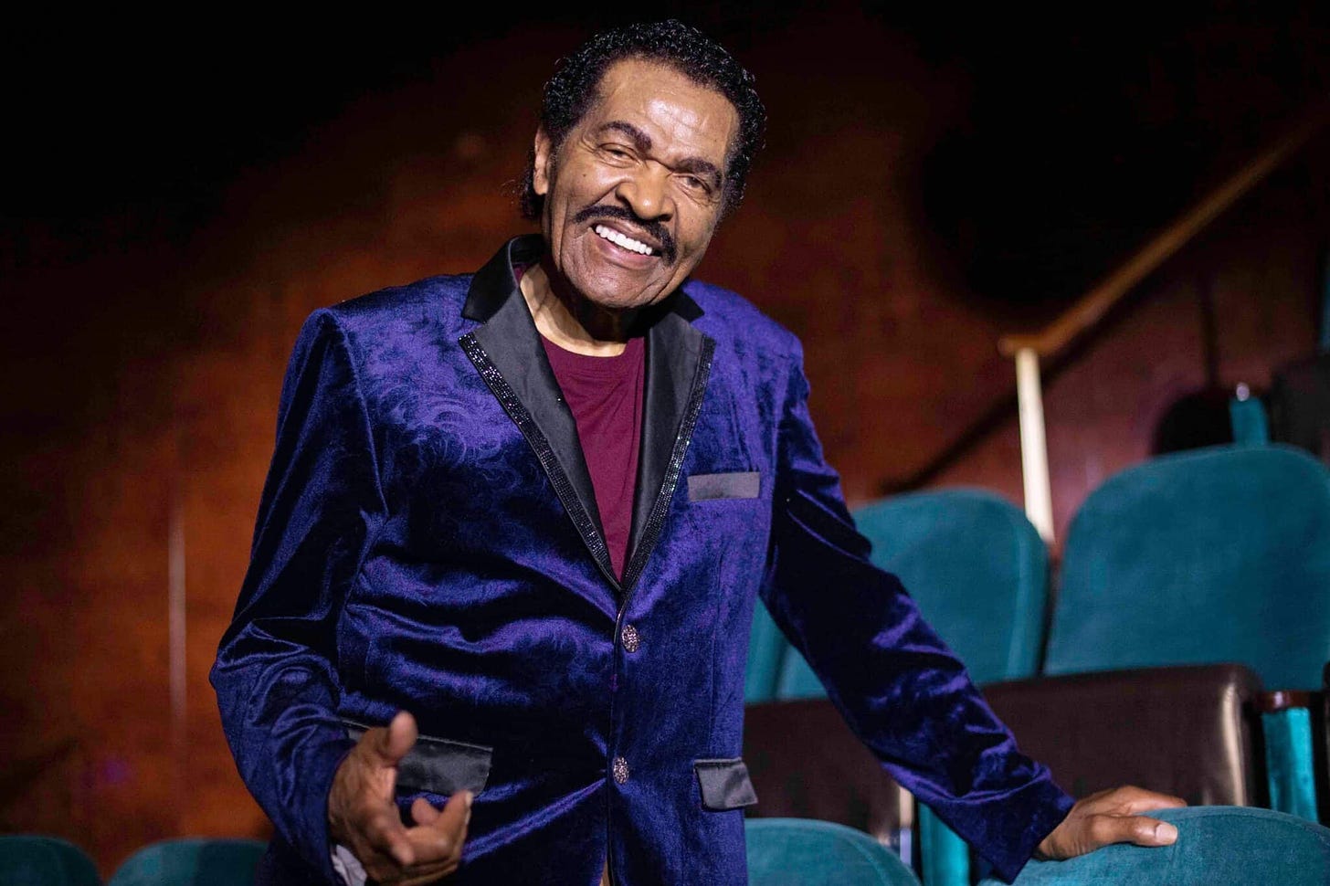Bobby Rush in a purple velvet jacket pointing at the camera