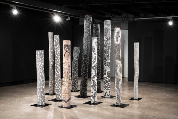 An installation of 11 poles, of various heights, some painted with stars and galaxies, others with various symbols. 