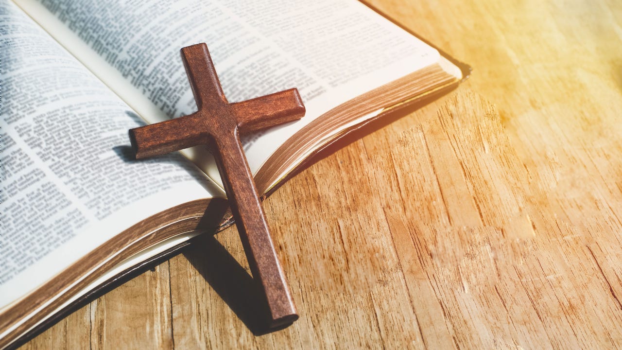 A wooden cross on an open Bible. 