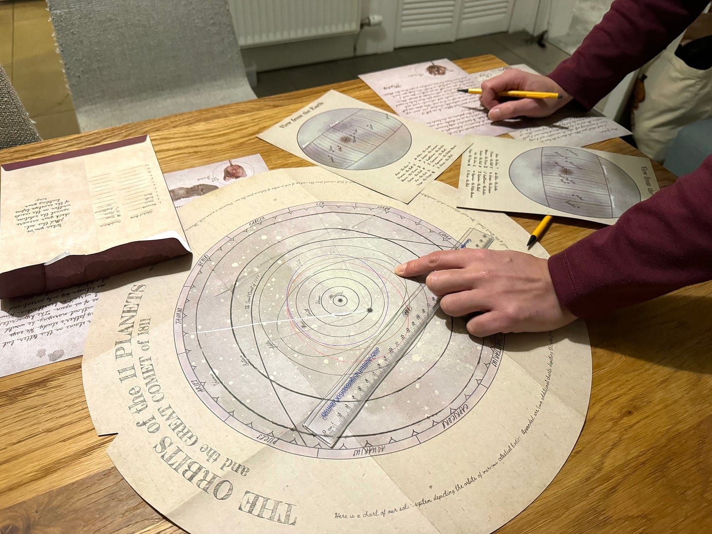 A hand points at a printed circular map of the solar system on a table