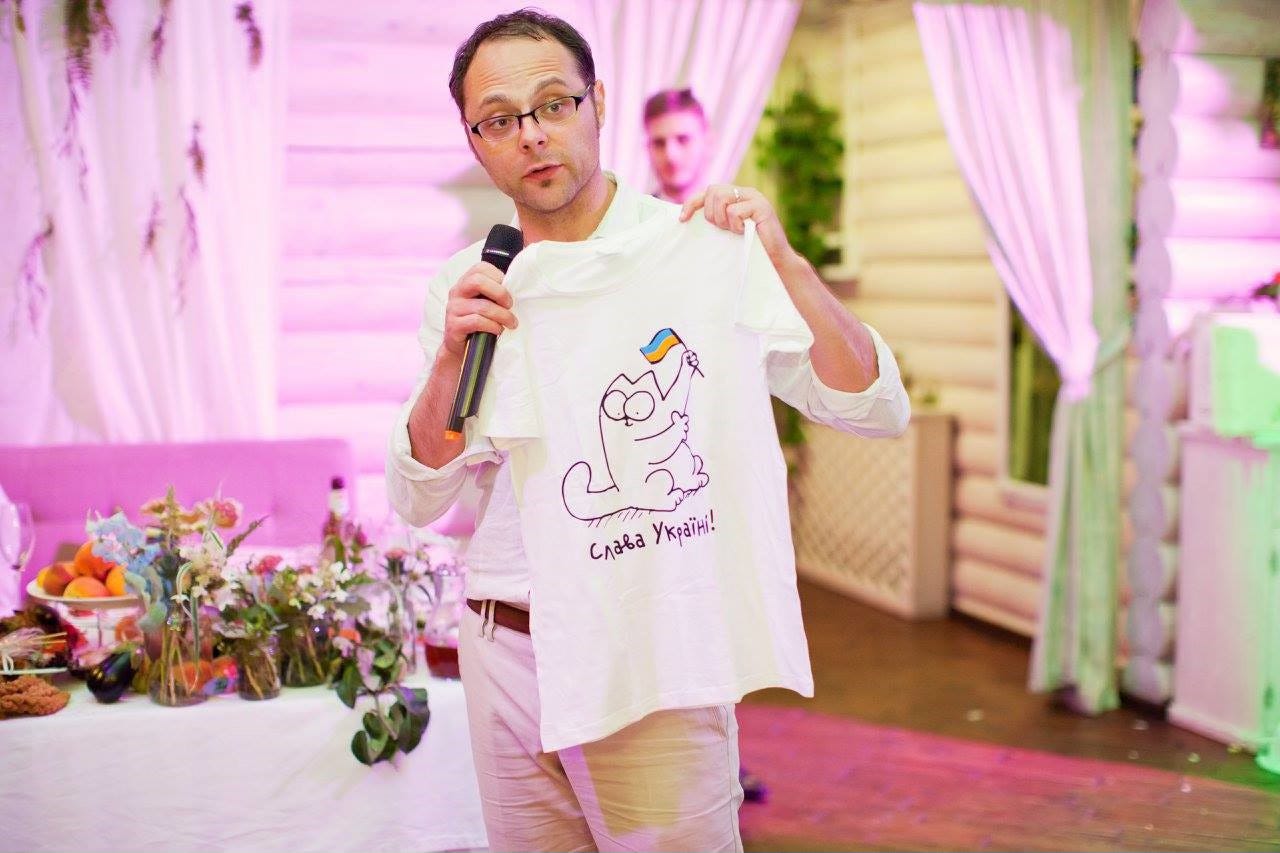 Man with microphone at a wedding holds up a t-shirt.